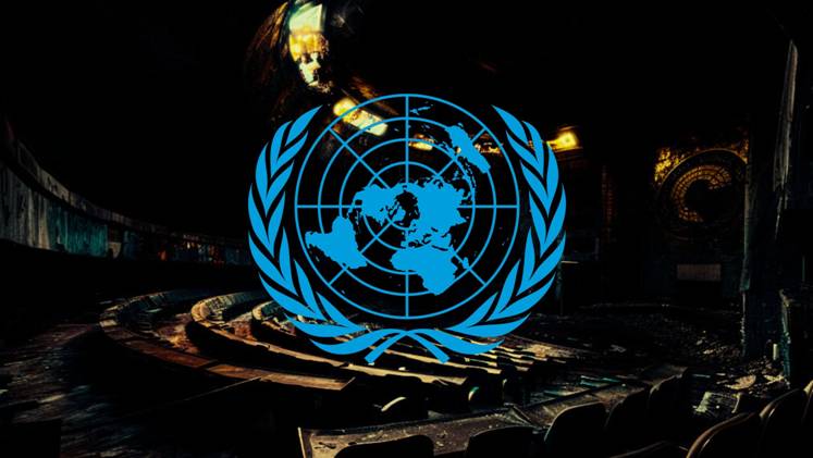 Blue United Nations emblem over a dimly lit, abandoned conference hall.